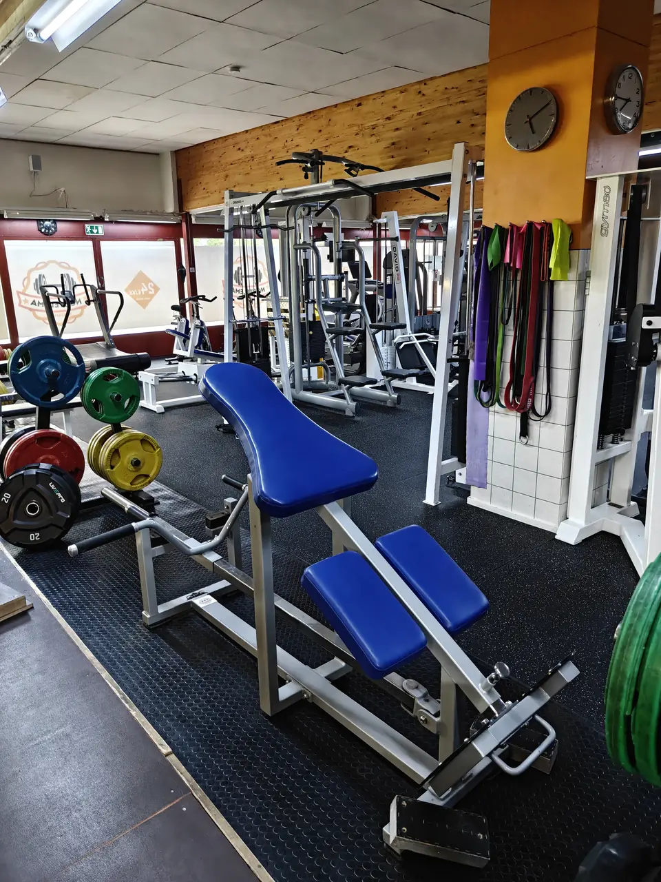 Incline bench, weight plates and resistance bands by the orange pillar