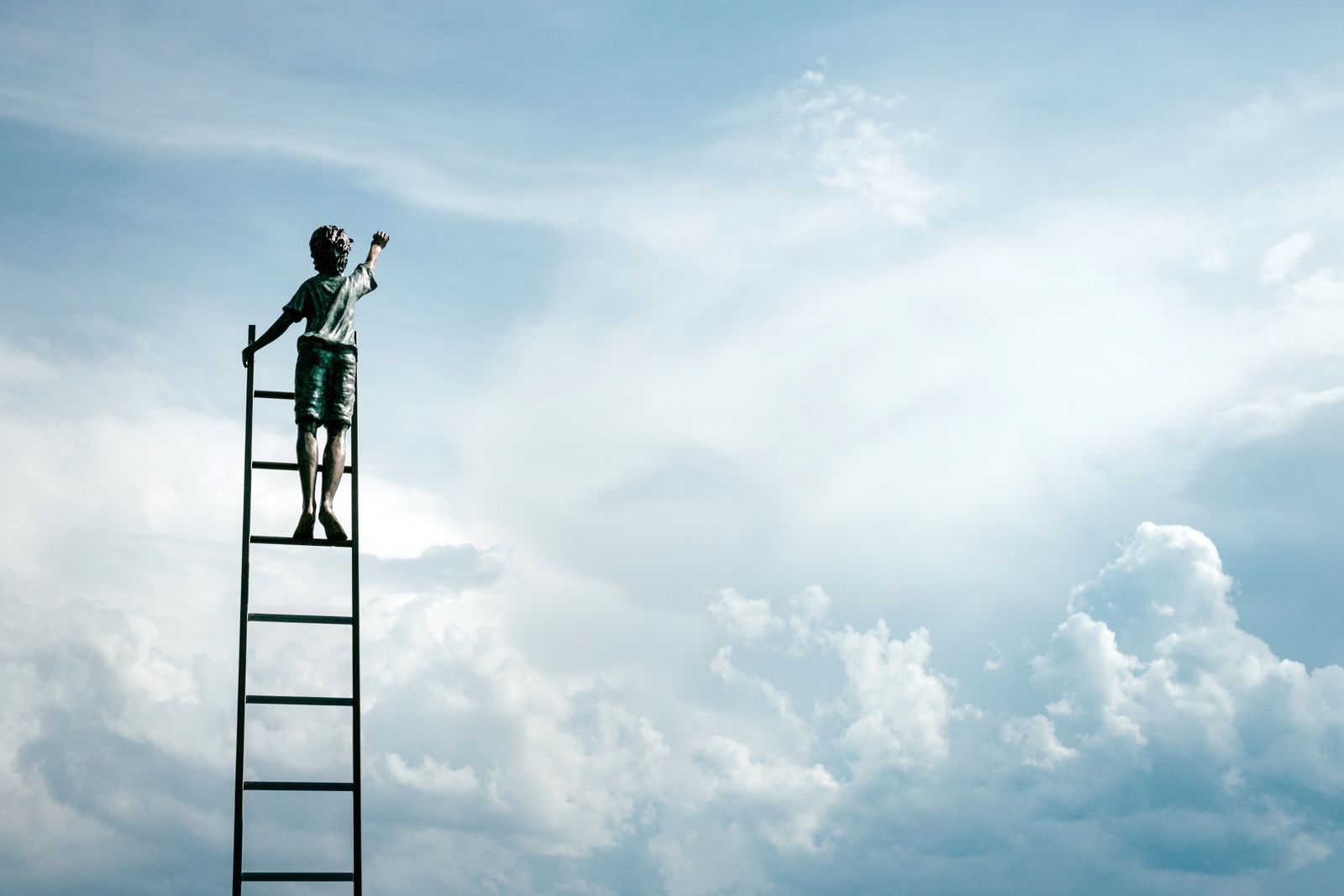 Person at the top of a ladder against the sky (stock photo)