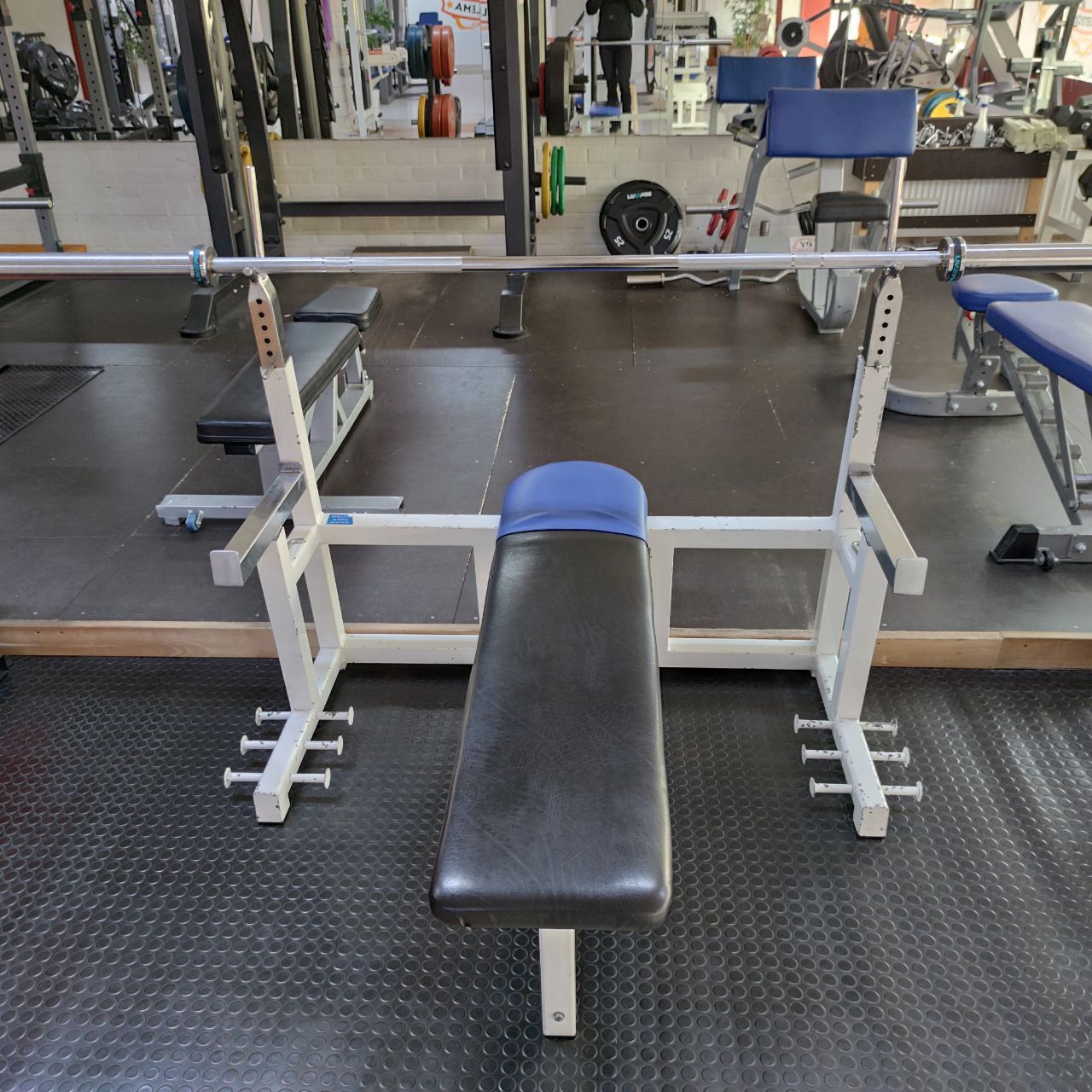 Bench press rack with a barbell and plates at Nostelema