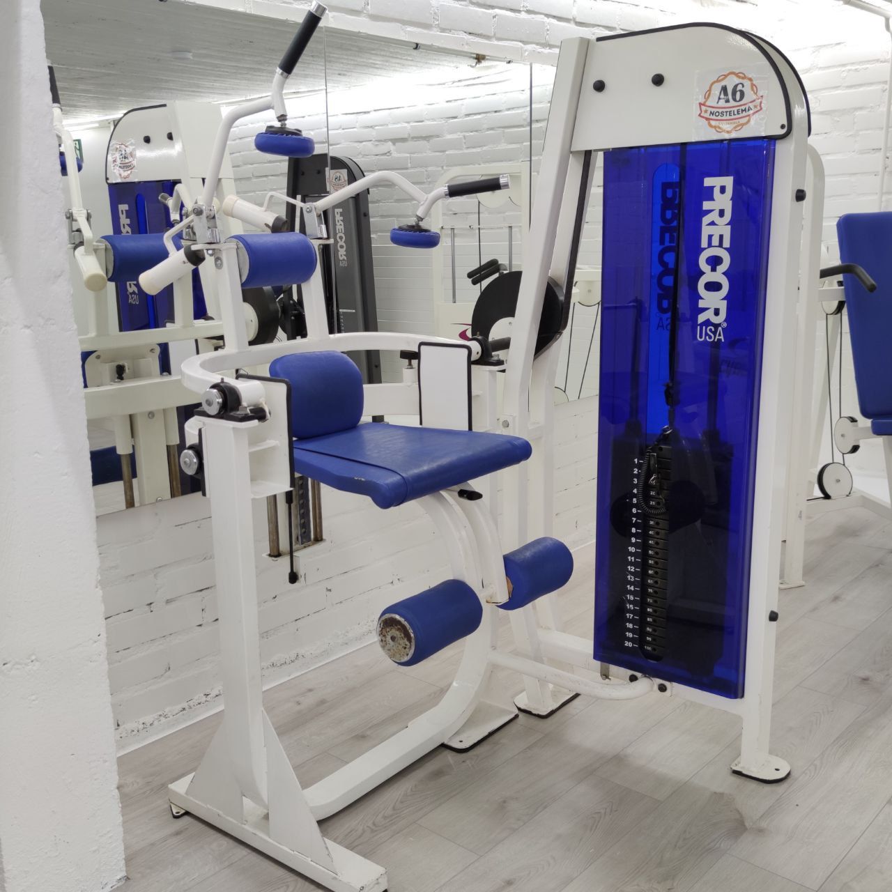 White-framed Precor ab crunch machine: seat, shoulder pads with handles and ankle rollers