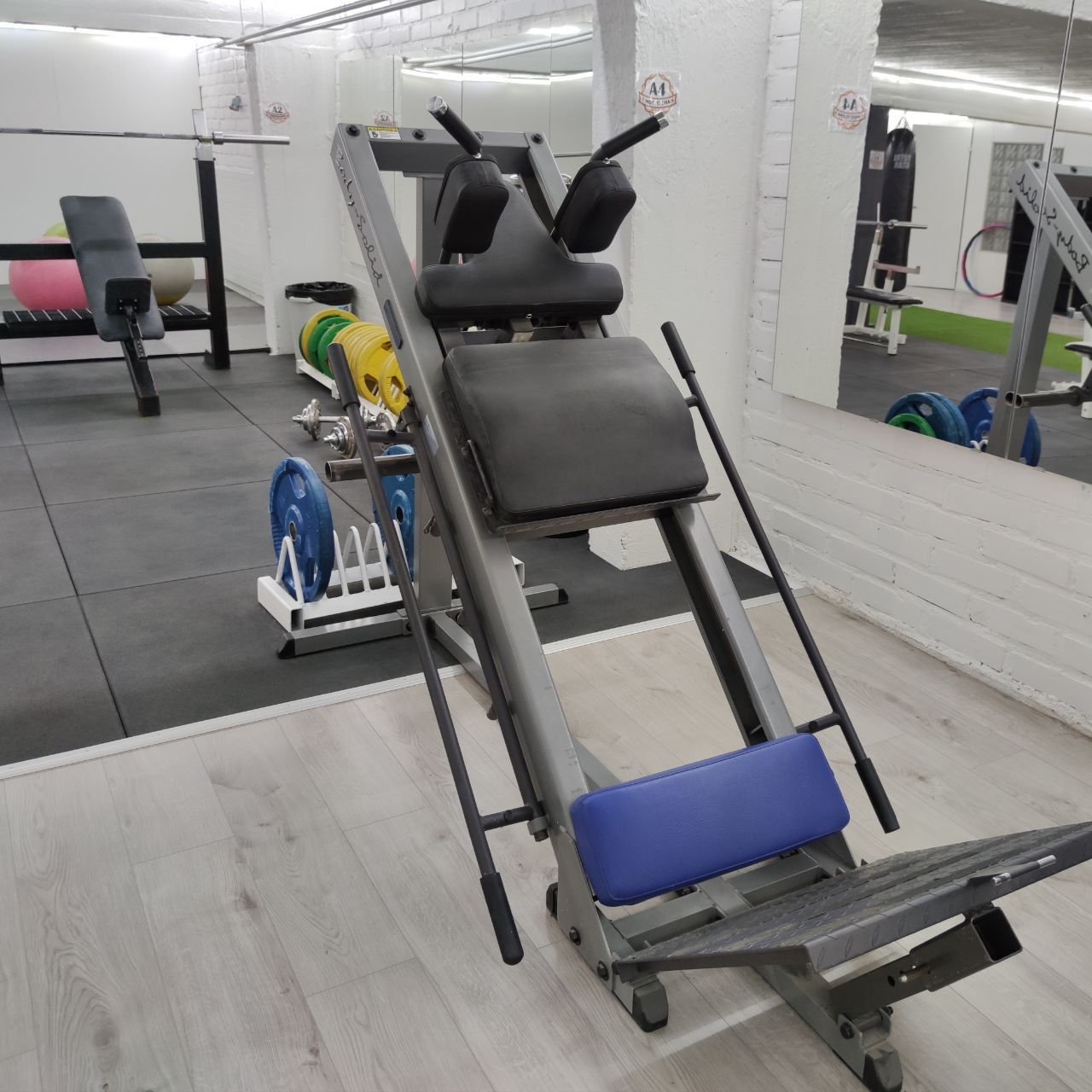 Hack squat machine with shoulder pads, a back support and a footplate
