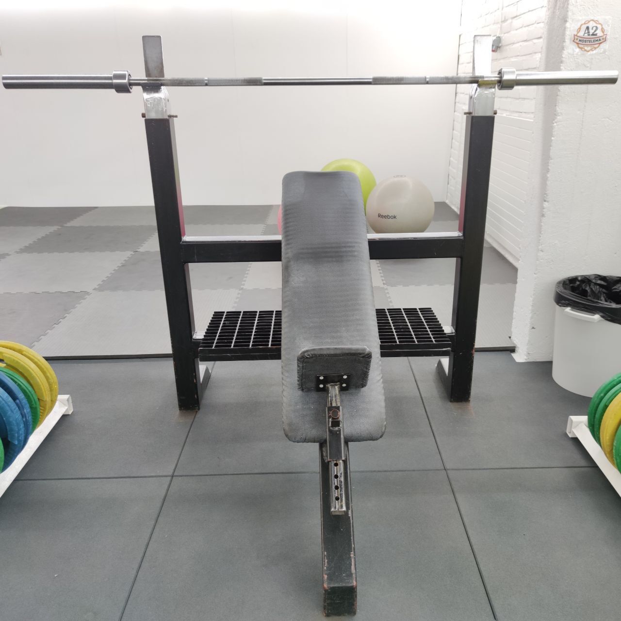 Black-framed bench press rack with an adjustable bench and a barbell with plates